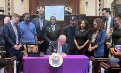 a group stands and looks on as NJ Governor Phil Murphy signs law