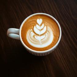 An overhead image of a coffee cup with pumpkin-colored liquid in a white coffee mug.